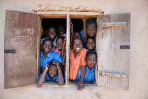 Groupe d’enfants souriants regardant par la fenêtre d’une école africaine